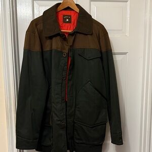 Orvis Upland Coat feels like oil cloth or tin cloth.  Button front wool collar